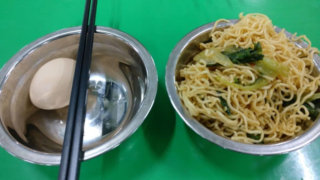 茶餐廳早餐：一碗炒麵配菜心，旁邊小碗盛著烚蛋