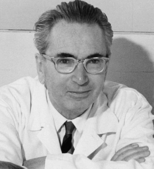 精神科醫生維克多・弗蘭克（Viktor Frankl）的黑白肖像照，戴眼鏡、身穿白袍雙手交疊