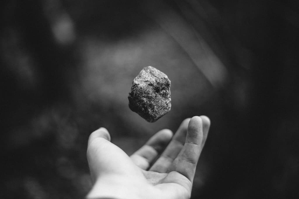 黑白照片:一塊石頭懸在半空,下方是一隻攤開的手掌
